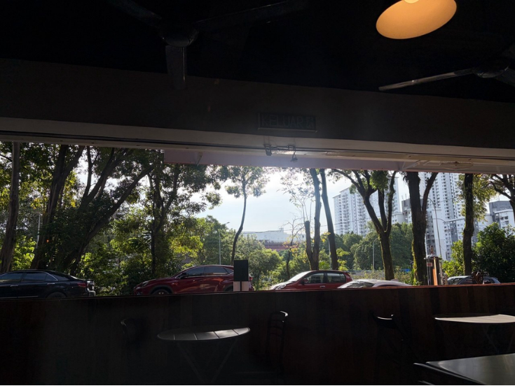 View from inside Strangers at 47 looking out to trees and parked cars in Petaling Jaya